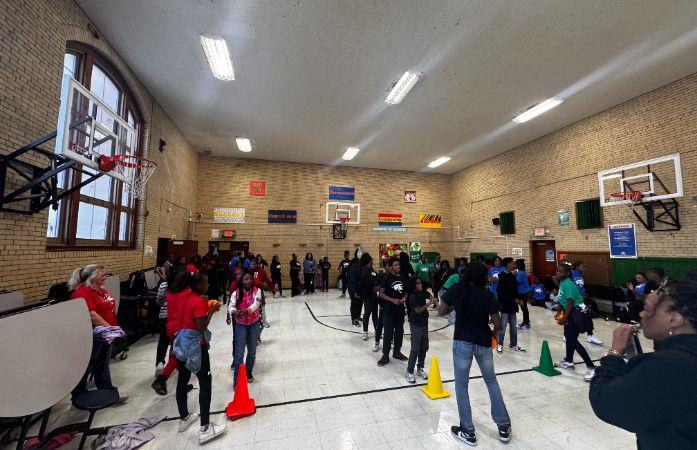 Students in a gymnasium lined up playing relay game.
